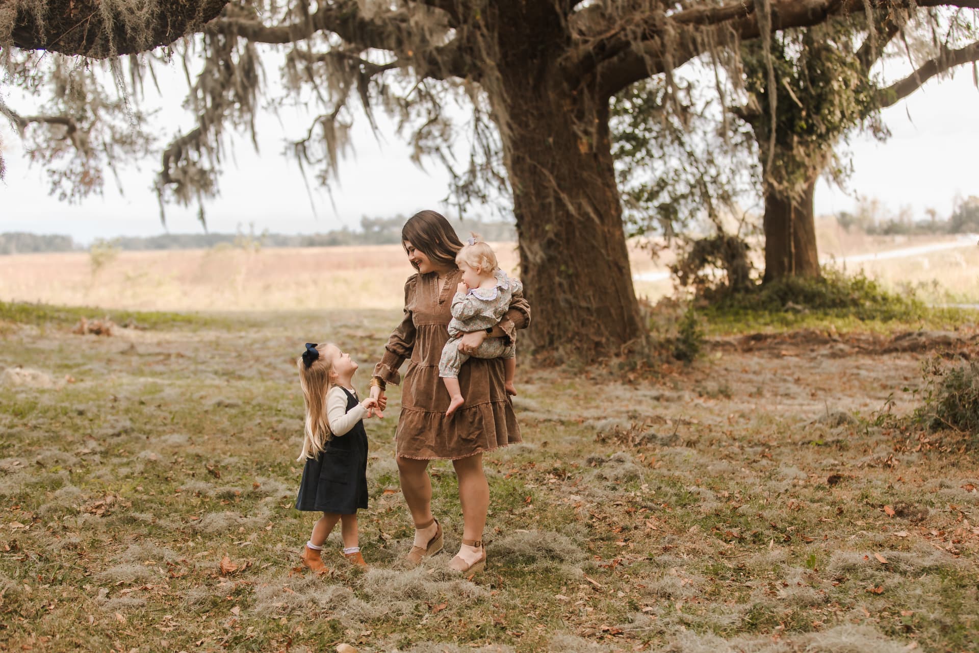 Kelsey with her daughters under a mossy oak tree