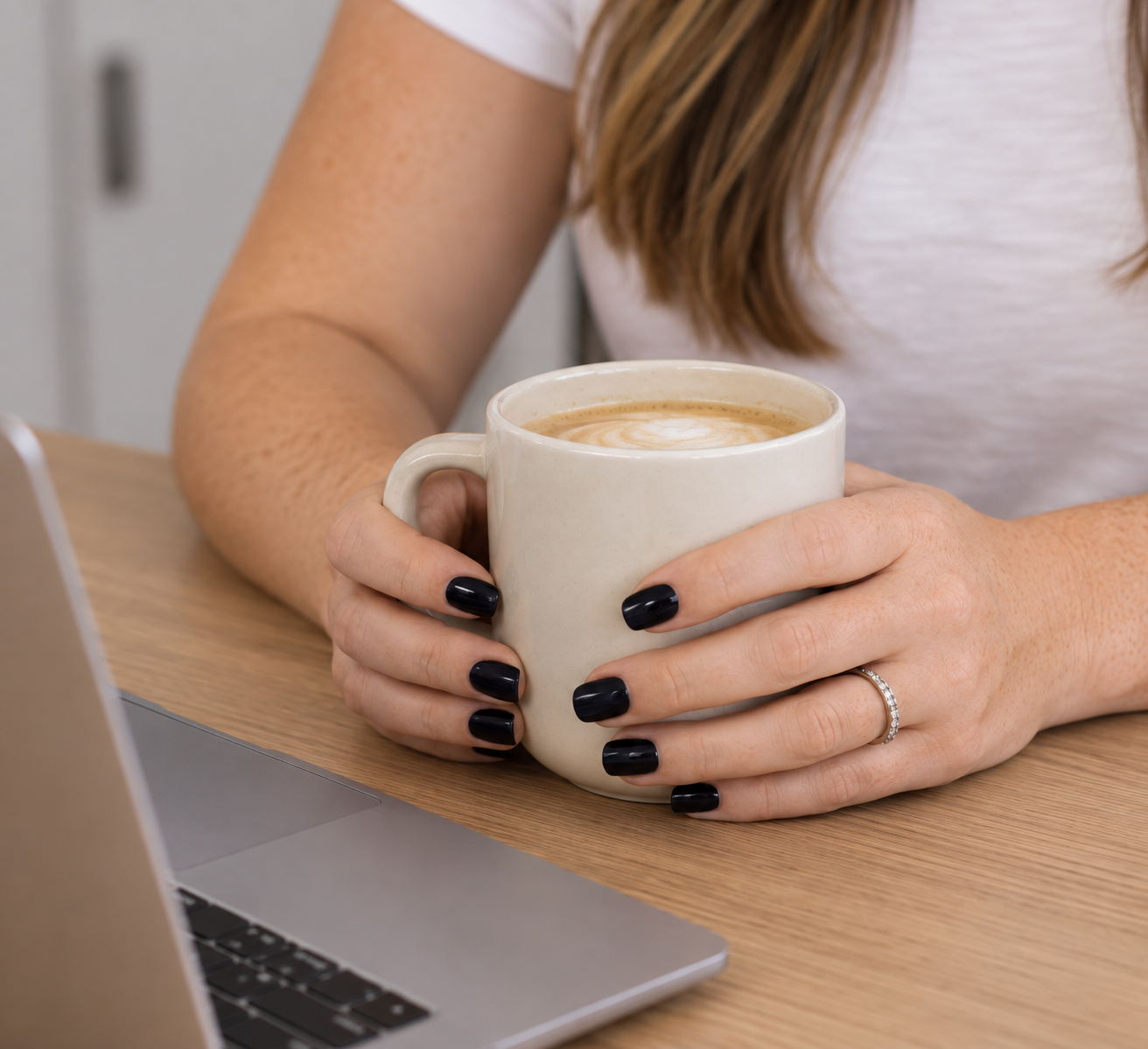 Kelsey holding a latte beside her laptop